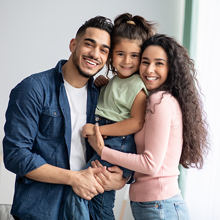 Smiling happy family with the parents holding their young daughter.