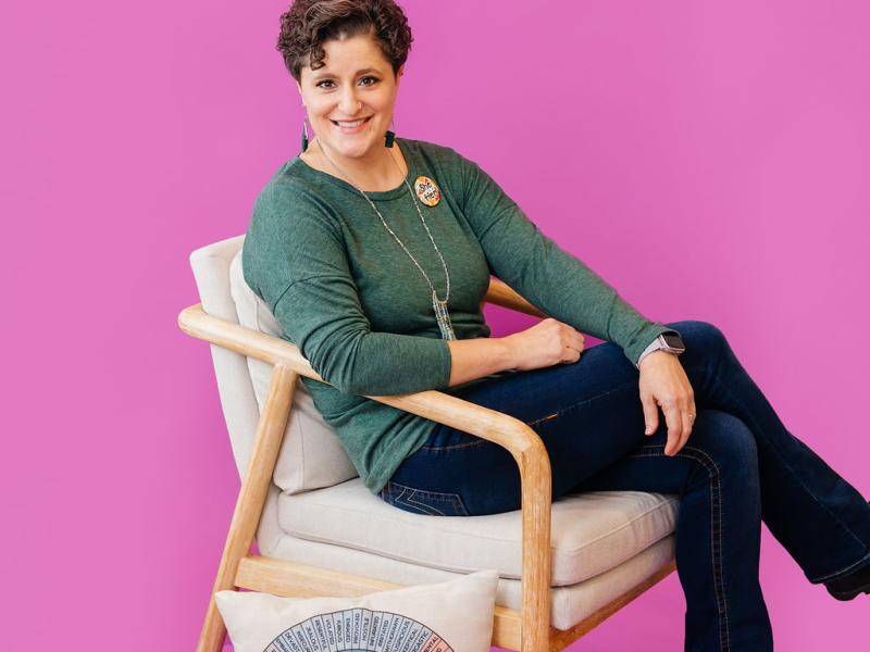 Kara Gloe sits in front of a magenta backdrop.