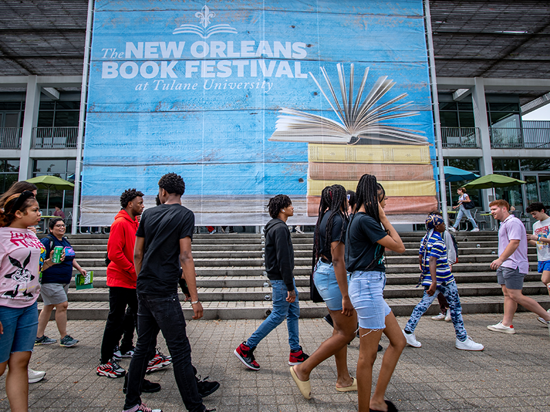 Tulane students walk past a New Orleans Book Festival banner on campus