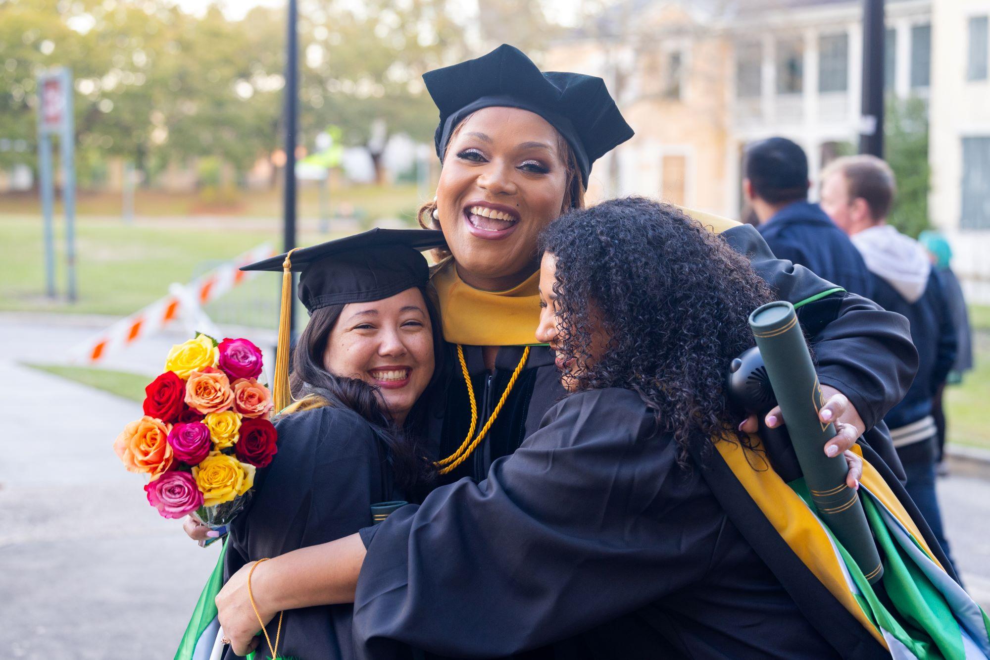 Alaiyia Williams smiles with two friends at graduation.