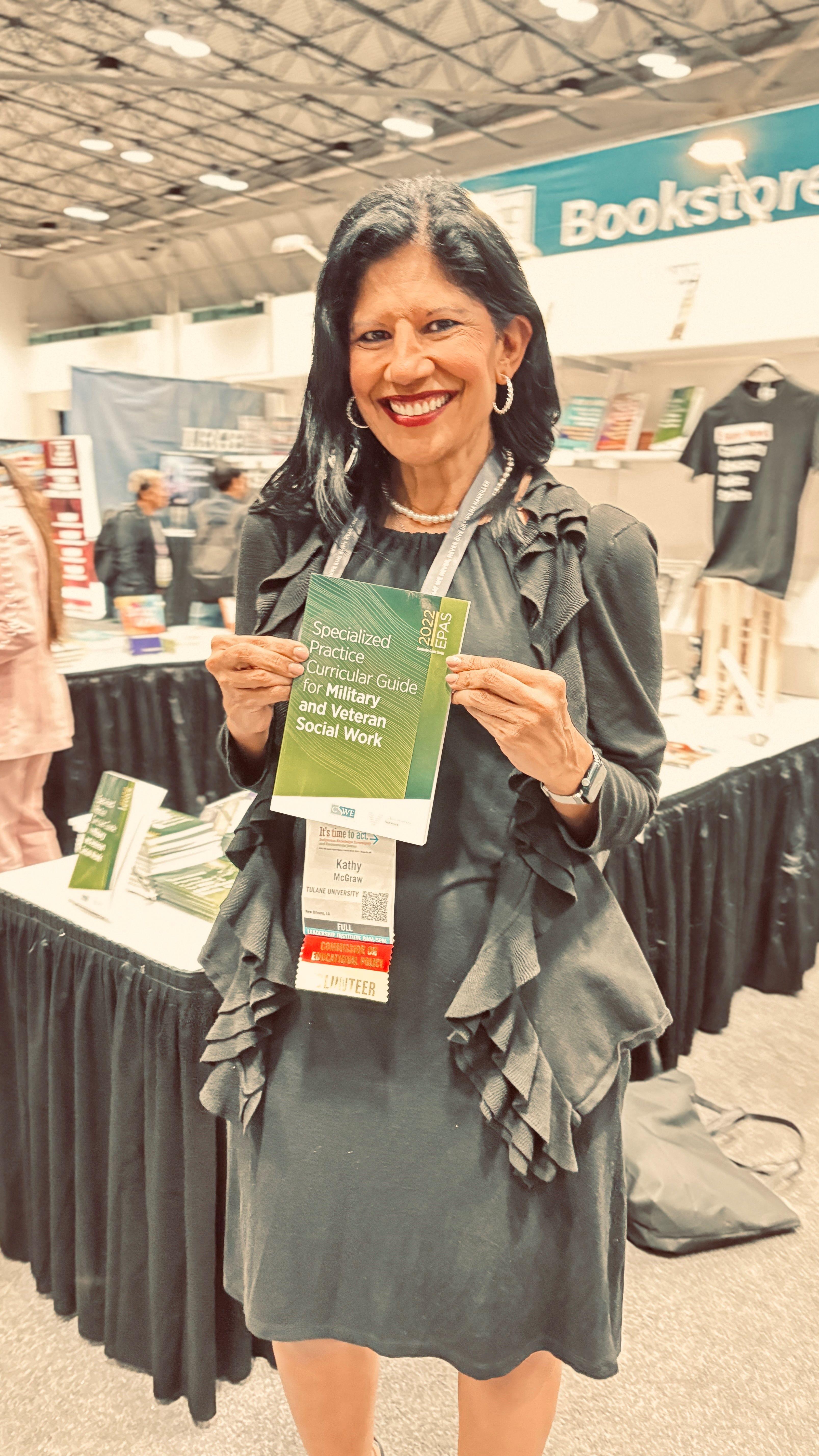 Dr Kathy Levy-Oqueli McGraw with her copy of the CSWE EPAS Specialized Curricular Guide for Military and Veteran Social Work.