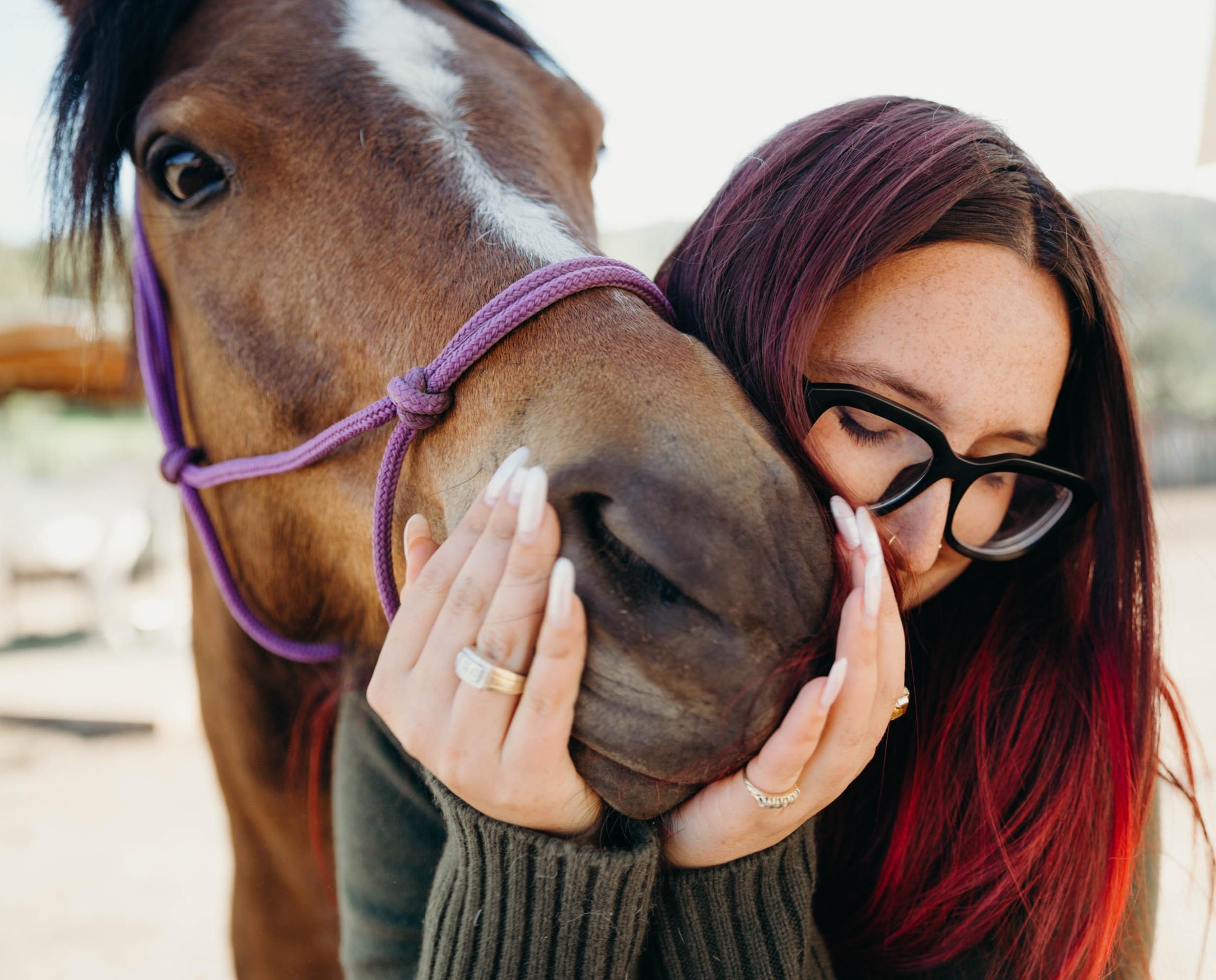 Drayton Doyle holds a brown horse's nose close to their own.