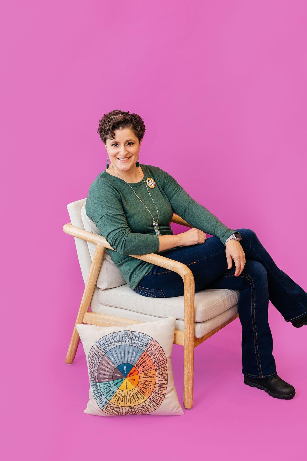 Kara Gloe sits in front of a magenta backdrop.