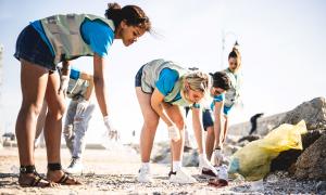 Students clean up a beach after a disaster.