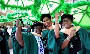 Three women smile while holding umbrellas