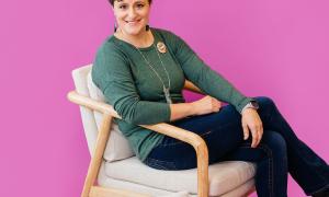 Kara Gloe sits in front of a magenta backdrop.